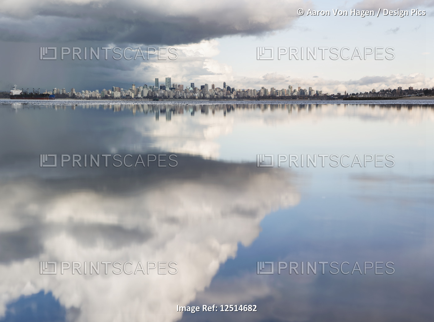 Distant view of the Vancouver skyline over the Pacific Ocean reflecting clouds, ...