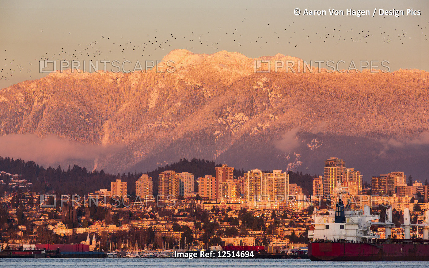 The North Vancouver skyline and Coast Mountains glowing at dusk and ships in ...