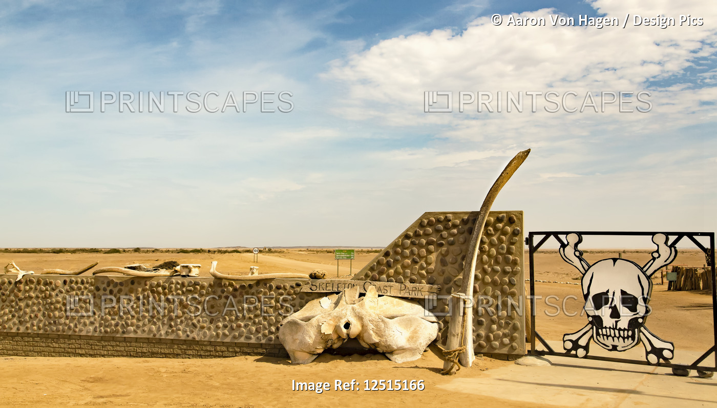 A closed gate with skull and crossbones in the Namib desert, Skeleton Coast; ...