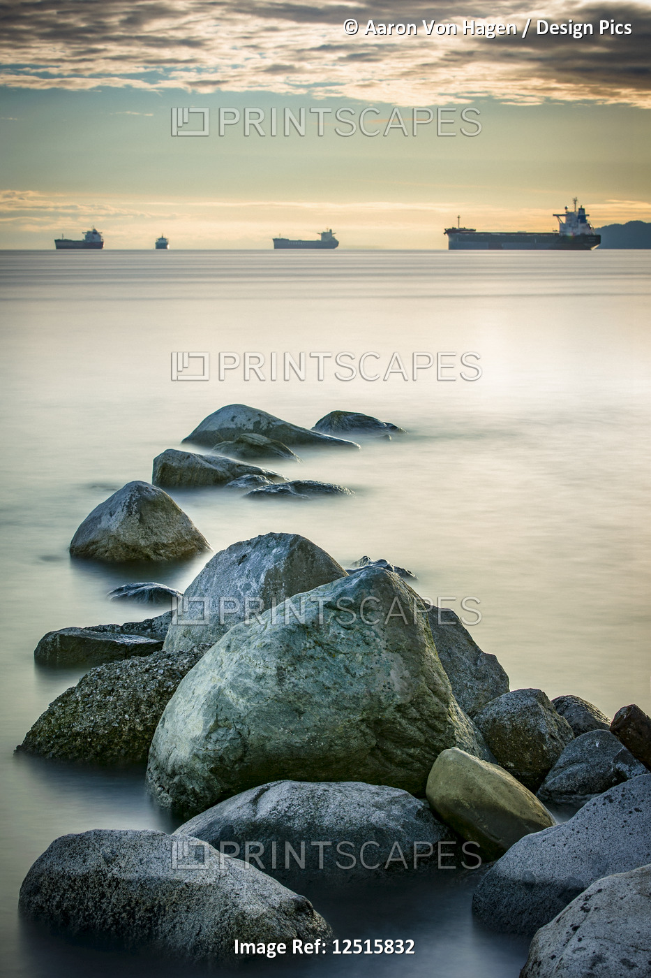 Ships out in the Pacific ocean off the coast of Stanley Park with rocks in the ...
